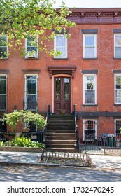 Decorative Dark Wood Front Door In Red Brick Row Home With Stoop Off Of The Sidewalk In Park Slope, Brooklyn In New York City