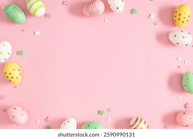 Decorative Easter eggs in beautiful patterns and sugar candies with empty space for text on a pink background. Top view