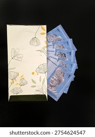 Decorative envelope with Malaysian Ringgit notes, symbolizing festive money-giving tradition during Hari Raya or Eid Mubarak. 