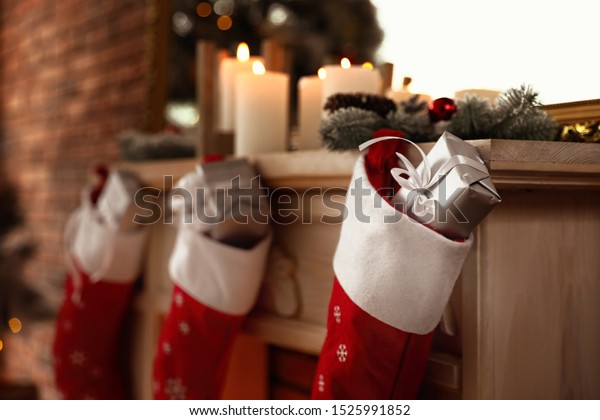 Decorative fireplace with Christmas stocking and\
gifts in stylish room\
interior