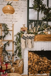 Decorative Fireplace With Christmas Stockings, Garlands And Gifts In Stylish Room Interior. Knitted Woolen Socks. Happy New Year And Merry Christmas.