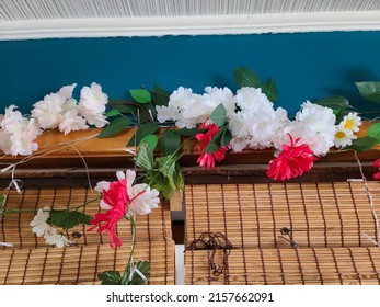 Decorative flowers hanging above a blind on top of the windows of a suburban home.