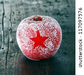 Decorative fresh ripe red Christmas apple frosted with a star pattern on an old vintage wooden table top, closeup in square format