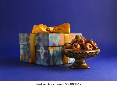 Decorative gift box with golden ribbon and dates. Islamic festive gift and dates. Stock photo. 