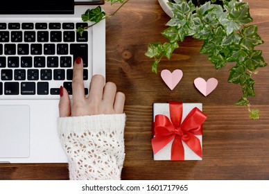 Decorative gift box with red bow, pink heart shaped papers and opened laptop computer on the dark wooden desk. Concept of online-shopping for Valentine's day, international Women's day and Christmas. - Powered by Shutterstock