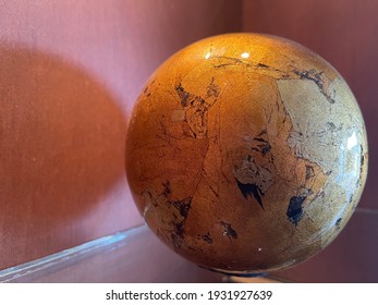 Decorative Papier-mâché Globe On Red Wooden Bookshelf