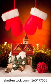 Decorative House Christmas Ornament With Red Gloves Hanging In Background