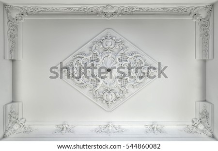 Decorative item made of white plaster on ceiling. Relief stucco interior