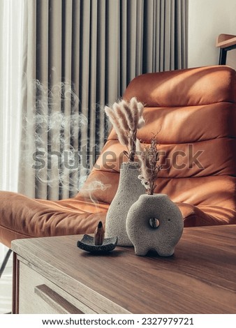 Decorative lava stone vases with dry flowers and incense cones on the table in the living room closeup