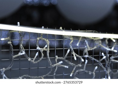 Decorative LED string lights hanging on a fence with soft bokeh background.