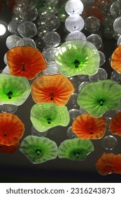 Decorative lights made of glass shaped like upside down opened umbrellas. Mixed color of green and orange. Artsy and contemporary design. Selective focus