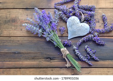 decorative metal heart among flowers of lavender on wooden background  