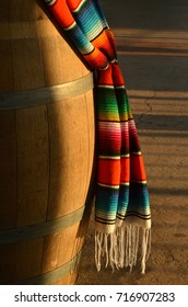 Decorative Mexican Woven Blanket Brilliant Colorful Stripes And White Hanging Fringe Hanging Over Wooden Barrel