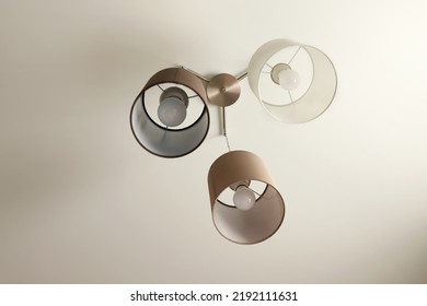 Decorative Modern Chandelier Hanging On The Ceiling Over Table In Modern Beige Room. Pendant Sconce Lighting Lamp. Modern Interior Design. High Quality Photo