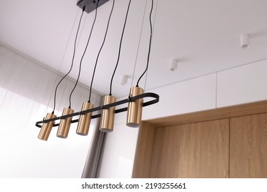 Decorative Modern Chandelier Hanging On The Ceiling Over Table In Modern White Room. Pendant Sconce Lighting Lamp. Modern Interior Design. High Quality Photo