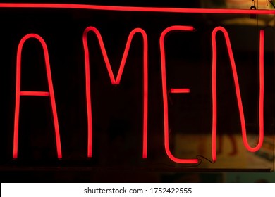 Decorative neon lights, deep red, with the word amen written.