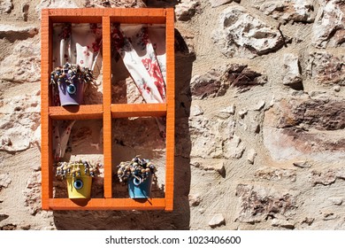 Decorative objects on old stone wall in sunny summer day.
