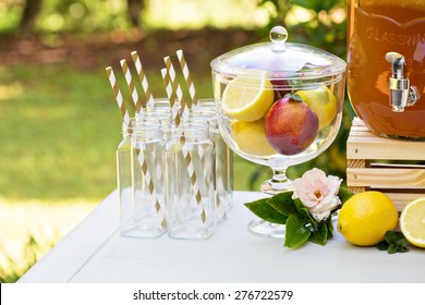Decorative outdoor party drink station with small bottles and homemade peach lemonade