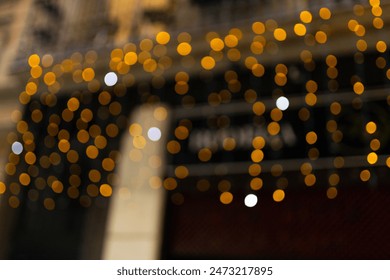 Decorative outdoor string lights at night time, Defocused Background, night city life backdrop, party time with Yellow bokeh balls - Powered by Shutterstock