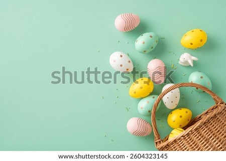 Decorative pastel Easter eggs with patterns are scattered around a basket on a green backdrop. This festive arrangement conveys the celebration of Easter and the joy of springtime.