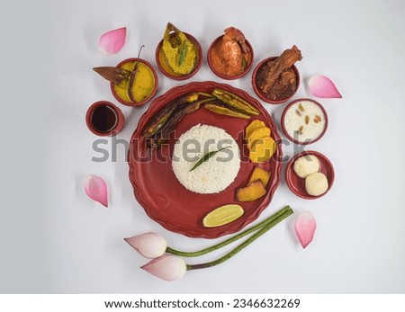 DECORATIVE PUJA BHOG THALI WITH RICE, DAL, HILSHA FISH, PRAWN FISH, MUTTON AND OTHER ITEM ISOLATED ON WHITE BACKGROUND. TOP VIEW WITH SELECTIVE FOCUS WITH GRAINY TONE. 