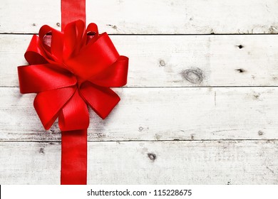 Decorative red ribbon and bow on a background of white painted rustic boards with copyspace - Powered by Shutterstock