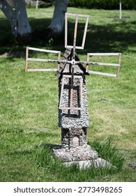 Decorative rustic garden windmill made of small stones. Unique stone and wood craft ornament for backyard decoration against a green lawn