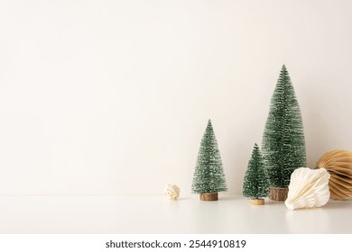 Decorative side view setup with mini snow-covered Christmas trees and paper ornaments in a Scandinavian minimalist style, placed against a neutral backdrop - Powered by Shutterstock