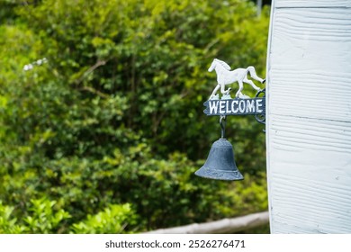 A decorative sign with a horse and bell, welcoming guests with a rustic charm. - Powered by Shutterstock