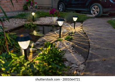 Decorative small garden sunlight, lanterns in a flower bed in green foliage. Garden design. Solar lamps in a row