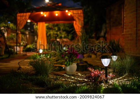 Decorative Small Solar Garden Light, Lanterns In Flower Bed. Garden Design. Solar Powered Lamp