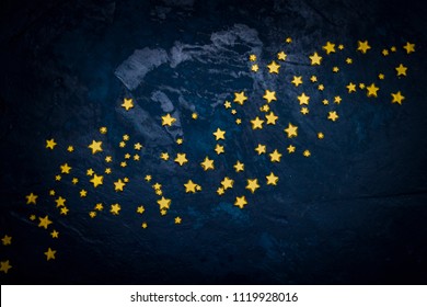 Decorative stars on a dark blue background. Concept of the night sky. Can be used as wallpaper or background. Flat lay, top view.
