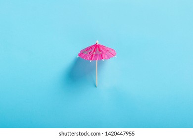 Decorative Umbrella For A Cocktail On A Blue Background. Flat Lay, Top View