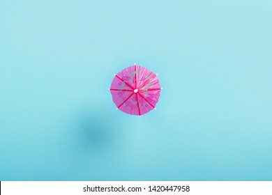 Decorative Umbrella For A Cocktail On A Blue Background. Flat Lay, Top View