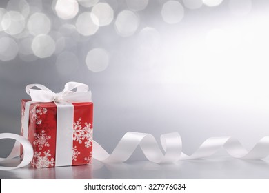 Decorative white gift box with ribbon against abstract background.