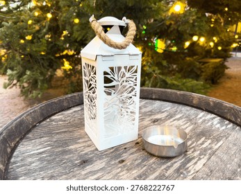 Decorative white lantern on rustic barrel surface among christmas lights.
