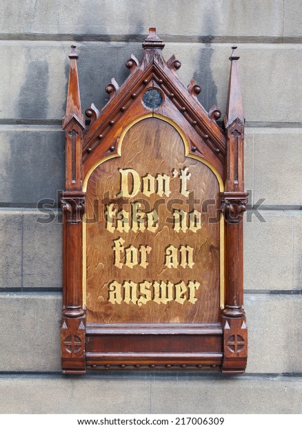 Decorative wooden sign hanging on a concrete wall\
- Don\'t take no for an\
answer