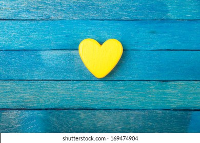 Decorative yellow heart on blue wooden background