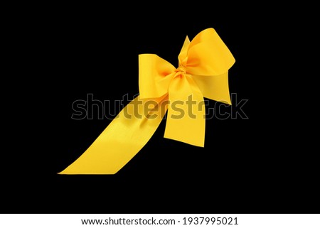 Decorative yellow ribbon and bow cut out and isolated on black background