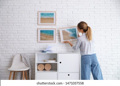 Decorator hanging picture on white brick wall in room. Interior design - Shutterstock ID 1471037558