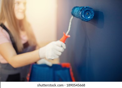 Decorator painter hand painting blue color wall with roller.