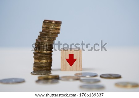 Decrease in income. Global financial crisis. Bankruptcy, lack of money. Stack of coins, wooden cube, arrow to down sign