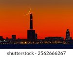 Decreasing moonset at 2% over an old thermal power plant with three chimneys, which measure 200 meters each. These chimneys are part of the Barcelona skyline.