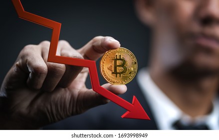 Decreasing Value of Bitcoin. Businessman Holding Bitcoin With Red 3D Arrow Down