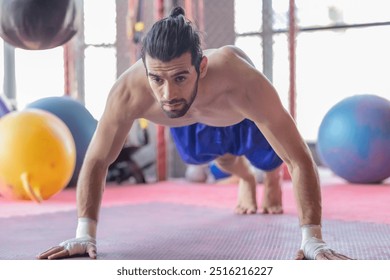 Dedicated boxer performs intense push up exercises in gym, showcasing strength and discipline. The image captures the athlete's muscular form and focused determination, highlight training environment - Powered by Shutterstock