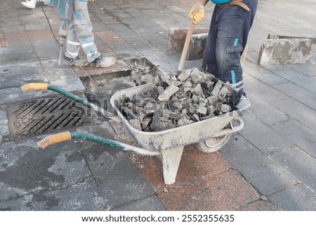 A dedicated Construction Worker with a Wheelbarrow fully Loaded with Heavy Stones and Materials