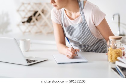 Dedicated Hostess Making Notes In Her Cookbook