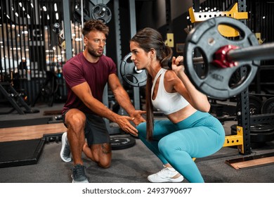 A dedicated male fitness instructor assisting his female trainee with her weightlifting exercise at the gym. - Powered by Shutterstock