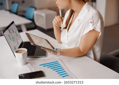 A dedicated professional analyzing data and emerging trends with digital devices in a sleek, modern office