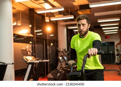 Dedicated sportsman exercising in gym. Fit male athlete is doing cardiovascular exercise. He is wearing sportswear.